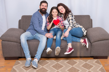 Enjoying every moment together. bearded man and woman with child hold red heart. happy family at home on weekend. mother and father love daughter. little girl with parents. trust and relative bonds