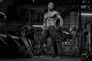 Fototapeta na wymiar Muscular man bodybuilder training in gym and posing muscle