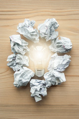 White crumpled paper balls folded on circle with light bulb inside. Concept of problem solution. Symbol of idea, innovation, inspiration, think different, think out of the box, leadership.