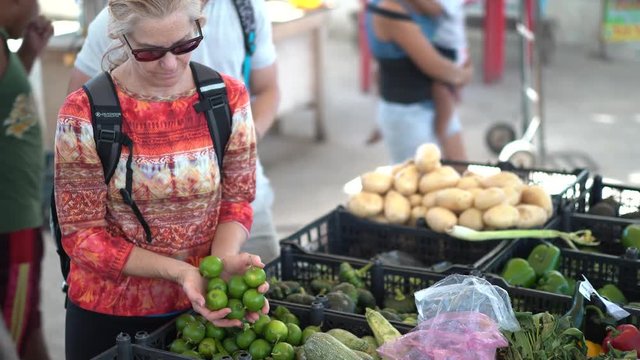 Tight Shot Of Mature Woman Choosing Limes At A Farmers Market.