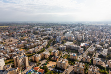 Aerial view of a residential neighborhood in a city during a cloudy and sunny sunrise. Taken in Netanya, Center District, Israel.