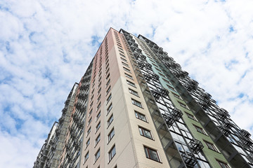 Fototapeta premium New residential building against the blue sky and white clouds. Housing construction, apartment panel house, real estate concept