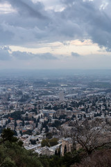 Naklejka premium Beautiful view of a city on the coast of Mediterranean Sea during a cloudy sunset. Taken in Haifa, Israel.
