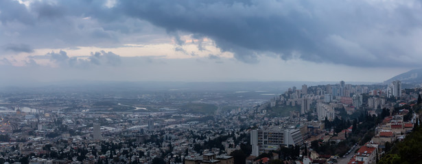 Fototapeta premium Beautiful panoramic view of a city on the coast of Mediterranean Sea during a cloudy sunset. Taken in Haifa, Israel.