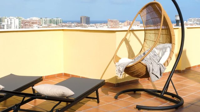 Hanging chair and sun beds in a sunny terrace of a relaxing summer holiday destination with sea view.