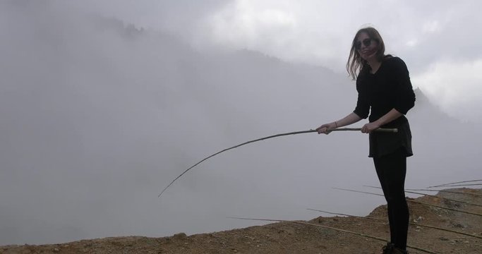 Female tourist taking out egg cooking on a fishing rod in Kwah Sinkiang Dieng, Wonosobo, volcanic crater, Java Island, Indonesia