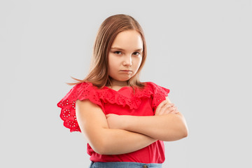 childhood and people concept - displeased girl in red shirt with crossed arms pouting over grey background