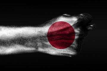 A hand with a painted Japan flag shows a fig, a sign of aggression, disagreement, a dispute on a...