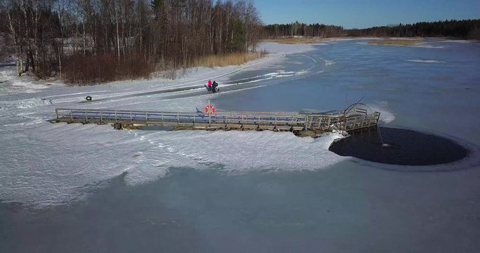 two women with stroller and kicksled on frozen ice, ongoing aeration project to oxygenate lake