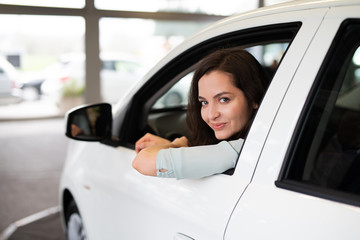 Junge hübsche Frau in einem neuen Auto in einem Autohaus 