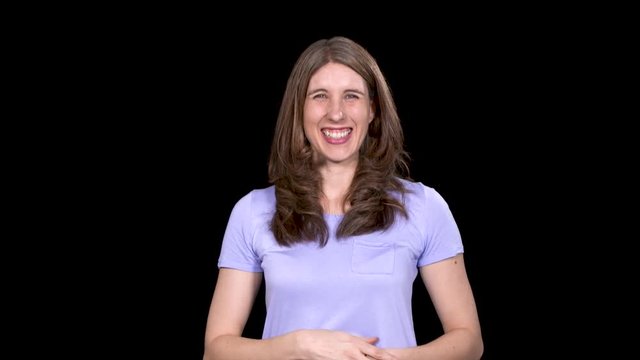 Caucasian female points and laughs at camera while on a black studio background