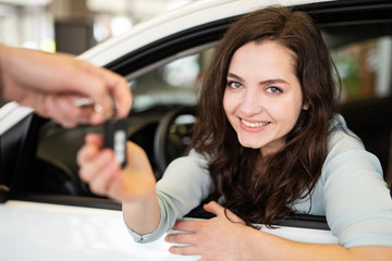 Obraz na płótnie Canvas Attraktive junge Frau nimmt den Autoschlüssel für ihr neues Auto entgegen 