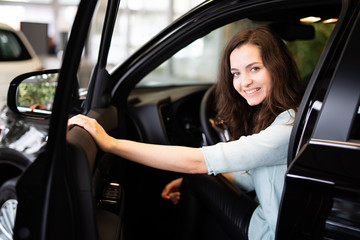 Hübsche junge frau in einem neuen Auto im Autohaus 