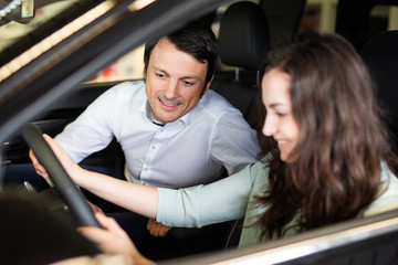 Fototapeta na wymiar Autoverkäufer erklärt einer Kundin die Ausstattung in einem Neuwagen 