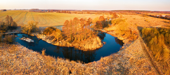 Bright sunrise over wild curved river aerial view.