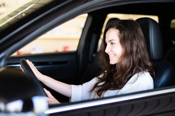 Obraz na płótnie Canvas Attraktive junge Frau freudig lächelnd in einem Auto 