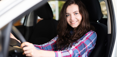 Fototapeta na wymiar Attraktive junge Frau sitzt Probe in einem neuen Auto 