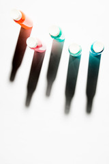 Bottle oaf acrylic paints colors in different tonality, top view long shadow on a white background