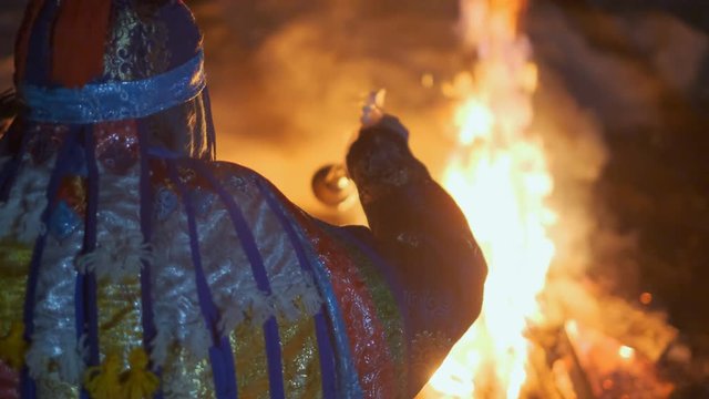 Silhouette of a shaman sitting by the fire.