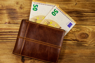 Wallet and fifty euro banknotes on wooden background
