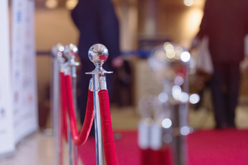 Silver stanchions with a red rope. Barrier, enclosed VIP area, protected enterance, private event,...