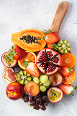 Delicious fruit platter pomegranate papaya oranges passion fruits on wooden board on white, top view, selective focus