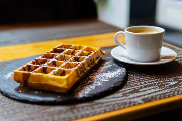 Cup of coffee and Belgian waffles with chocolate