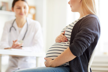 Mid section portrait of unrecognizable pregnant woman listening to obstetrician in doctors office lit by warm sunlight, copy space