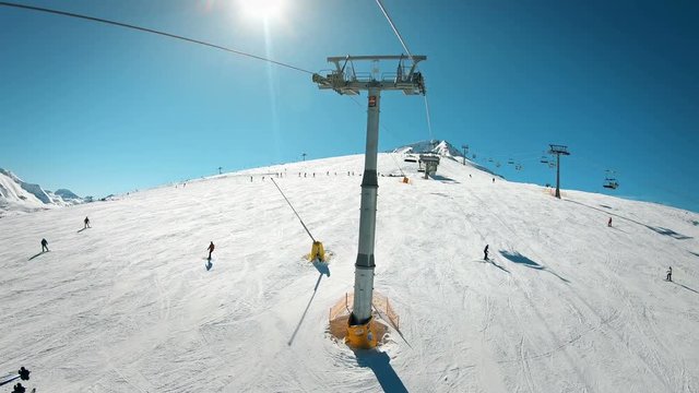 Pov of skier on ski lift arriving at top summit of mountain ski slopes in sunny day