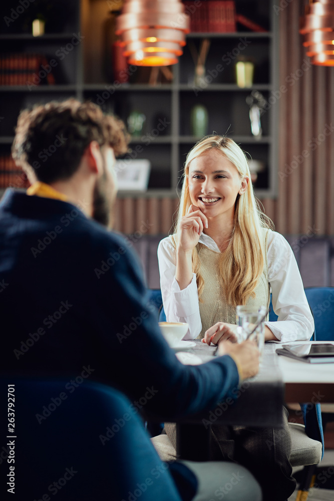 Wall mural smiling caucasian blonde businesswoman dressed smart casual discussing with her male colleague about