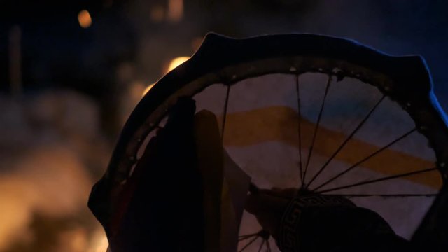 The silhouette of a shaman's tambourine near the fire.