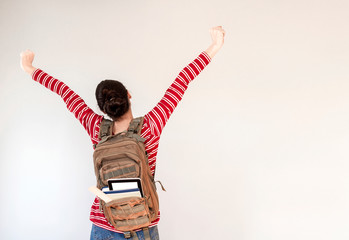 student with backpack arm raised, holding books