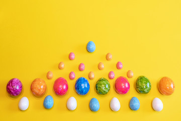 Fototapeta na wymiar A lot of colorful Easter eggs on a yellow background. Top view, minimal Easter concept. Happy Easter card with free, empty space.
