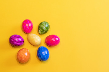 Fototapeta na wymiar Eight colored Easter eggs on a yellow background. Top view. Happy Easter card with free, empty space. Minimal Easter concept.