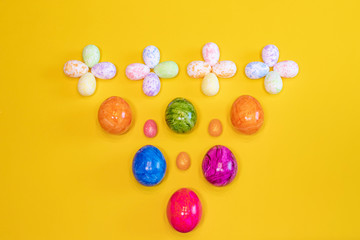 A lot of colorful Easter eggs on a yellow background. Top view, minimal Easter concept. Happy Easter card  with free, empty space.