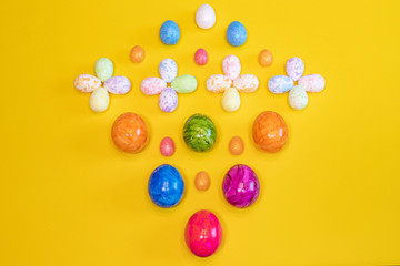 A lot of colorful Easter eggs on a yellow background. Top view, minimal Easter concept. Happy Easter card  with free, empty space.