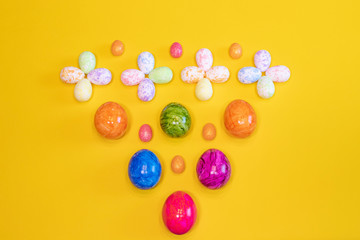 A lot of colorful Easter eggs on a yellow background. Top view, minimal Easter concept. Happy Easter card  with free, empty space.