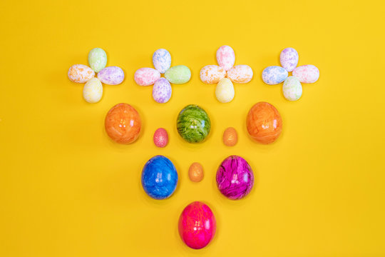 A lot of colorful Easter eggs on a yellow background. Top view, minimal Easter concept. Happy Easter card  with free, empty space.