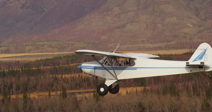 Pilot flies small airplane over Alaska landscape, aerial