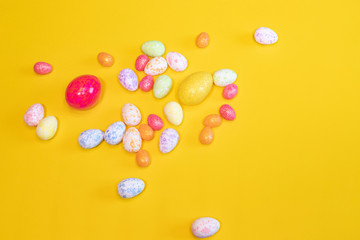 A lot of colorful Easter eggs on a yellow background. Top view, minimal Easter concept. Happy Easter card  with free, empty space.