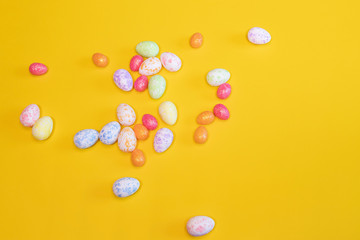 A lot of colorful Easter eggs on a yellow background. Top view, minimal Easter concept. Happy Easter card  with free, empty space.