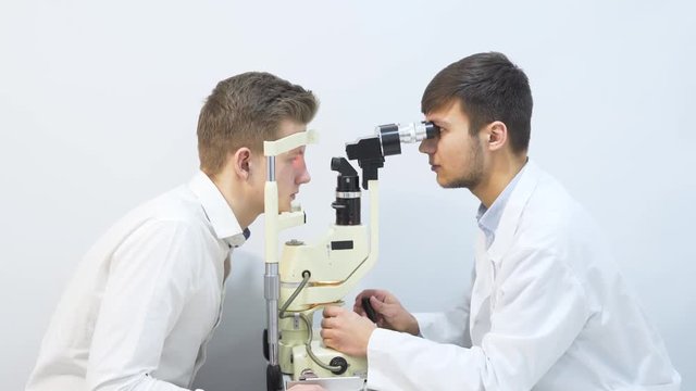 Male Optician Examining Male Patient Eyes While Using Special Equipment