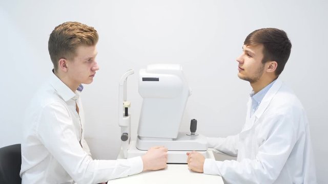 Male Optician Speaking To Male Customer.