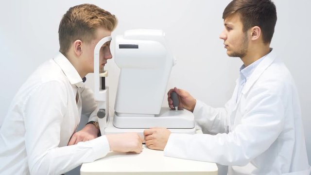 Male Optician Examining Male Patient Eyes Using Equipment