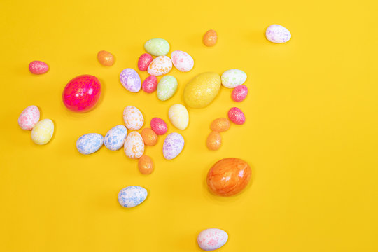 A lot of colorful Easter eggs on a yellow background. Top view, minimal Easter concept. Happy Easter card  with free, empty space.