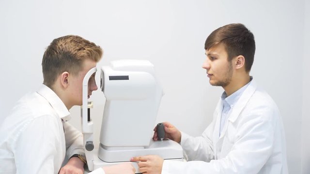 Male Optician Examining Male Patient Eyes While Using Equipment During Checkup