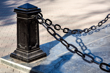 protective barrier of black iron pillar with a chain enclosing the marble apostment of the monument.
