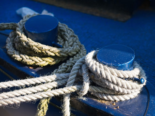 Fototapeta na wymiar Mooring ropes tied to blue iron bollards of the boat