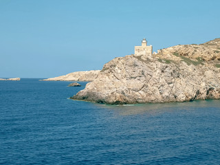 Fototapeta na wymiar sailing past the lighthouse in ormos harbor on the island of ios