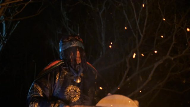 The shaman beats the drum and sings a song.